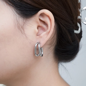 Close-up of dual-layer silver-tone U-shaped earrings with a polished mirror finish