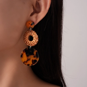 Detail view of Bohemian three-tier earrings with amber resin and woven rattan rings