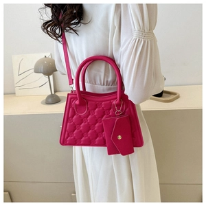 Detail of rose red embossed square bag with matching mini coin purse charm and shoulder strap