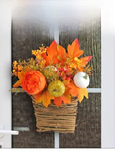 Close-up of harvest basket with maple leaves and pumpkins on a wooden door