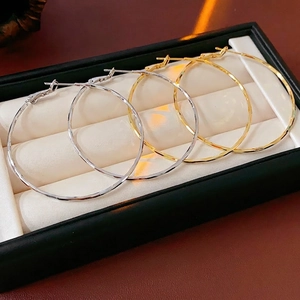 Grandes créoles polies dorées et argentées présentées dans une boîte à bijoux noire de luxe
