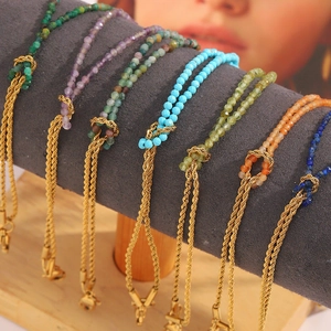 Detail of 18K gold braided chain bracelets with colorful natural stones on a jewelry display