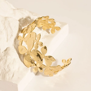 Detail of 18K gold-plated stainless steel cuff bracelet featuring hollow floral patterns