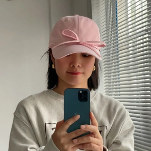 Detailed close-up of a pink satin bow decoration on a feminine breathable baseball cap