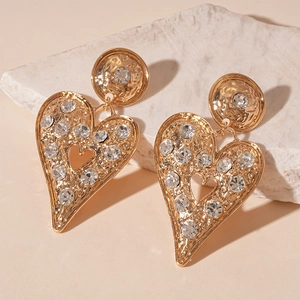 Detail of gold heart earrings with hammered metal texture and sparkling rhinestones