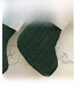 Vue détaillée de la texture de maille torsadée vert foncé du bas de Noël tricoté
