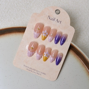 Detail of almond press-on nails with purple gradients, shell texture, and 3D floral accents