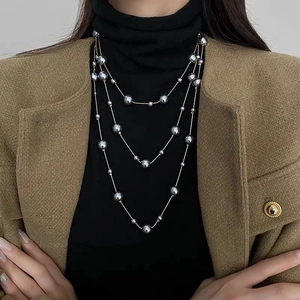 Détail du collier de perles multicouche avec perles grises et chaîne dorée fine sur mannequin