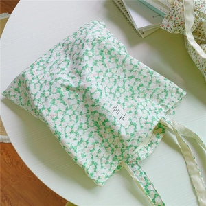 Detail shot of the green floral cotton tote bag with vintage text patch and soft handles