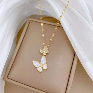 Macro detail of gold-plated butterfly necklace with white shell and zircon on silk