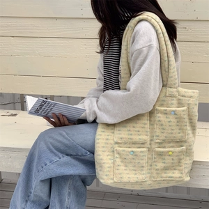 Detailed texture of plush tote bag with colorful buttons and four front pockets