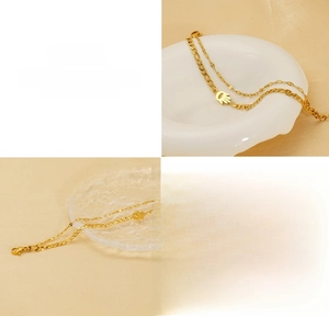 Detail of 18K gold plated double layer Hamsa hand charm bracelet on a ceramic plate