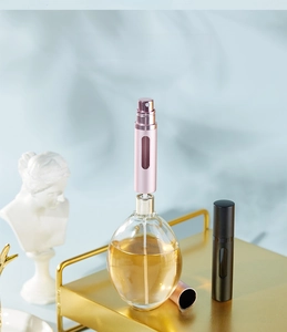 Detail of refillable perfume atomizer showing the bottom filling valve and pink metal shell