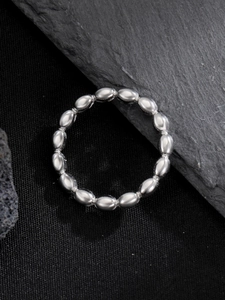 Macro detail of a silver beaded stainless steel ring on a dark textured background