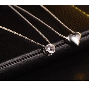 Elegant double-layered silver heart and zircon necklace on black leather background