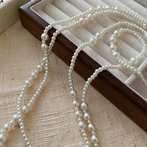 Dettaglio di una collana di perle vintage a strati su un vassoio per gioielli in legno