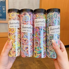 Close-up of four transparent jars filled with colorful elastic hair bands held by hands
