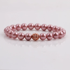 Detailed macro view of pink pearl bracelet with rose gold hollow metal crystal charm