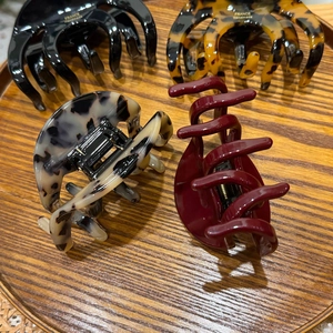 Set of four assorted acetate claw clips featuring marble and leopard patterns on wood tray