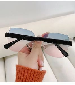 Detail showing the gradient blue-pink rimless lenses and wide black temples on the sunglasses