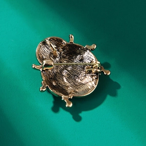 Detailansicht der Rückseite der goldenen Marienkäfer-Brosche mit Nadel und Öse