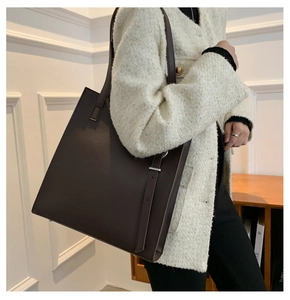 Minimalist large-capacity chocolate leather tote bag shown on model for sizing reference
