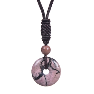 Macro detail of a round pink stone pendant with a hand-woven brown adjustable cord necklace