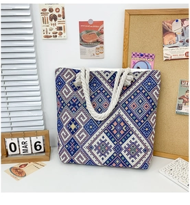 Detail of blue and white geometric embroidery on a large canvas tote bag with rope handle