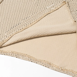 Vue macro des paillettes champagne et détails des coutures fines sur la robe