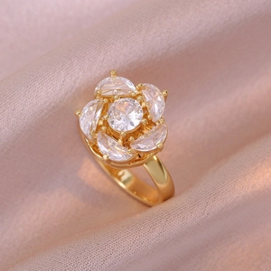 Bague fleur dorée avec pétales en zircon étincelants sur fond de soie rose doux