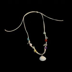 Gros plan d'un collier de plage fait main avec perles colorées et pendentif coquillage