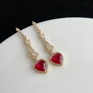 Détail de pierres précieuses rouges en forme de cœur sur des boucles d'oreilles dorées