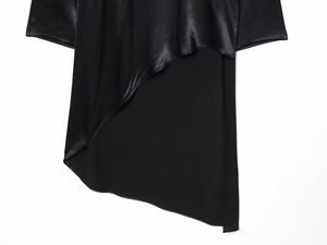 Détail de chemise noire asymétrique montrant la texture de satin et tissu mat