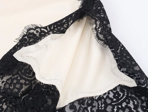 Detailed view of fine black eyelash lace trim on smooth beige satin fabric surface