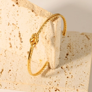 Detailed close-up of a 18K gold-plated stainless steel twisted knot cuff bracelet