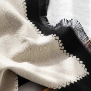 Close-up of color-block scarf featuring sawtooth stitching and fine fringe details