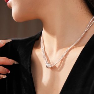 Close-up of double-layer necklace with large pearl pendant and silver bead chain