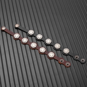 Detail of brown and black leather bracelets featuring star-shaped metal studs and snap closure