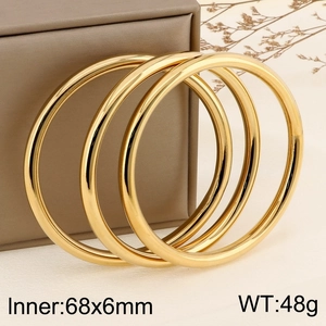 Three 18k gold-plated 6mm hollow stainless steel bangles leaning on a brown jewelry box