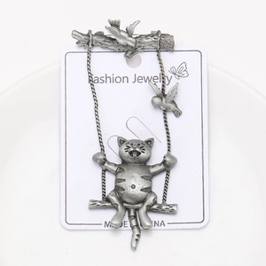 Close-up of vintage silver cat on swing brooch with bird detail on display card