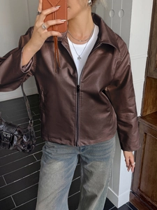 Selfie allo specchio che mostra la vestibilità di una giacca corta in pelle marrone con zip
