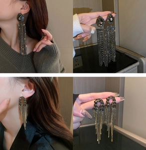 Macro detail of elegant U-shaped rhinestone tassel drop earrings in gold and charcoal finishes