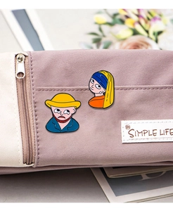 Detail of cartoon enamel pins showing Girl with a Pearl Earring and Van Gogh on a pouch