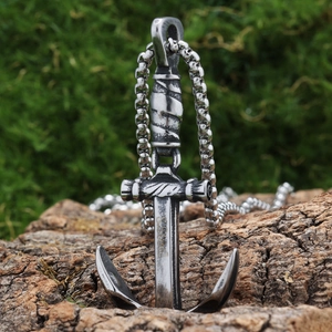 Detailed view of silver anchor pendant with S.Steel engraving on textured tree bark