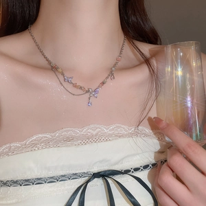 Close-up of double-layered butterfly necklace with colorful stones on model wearing white lace