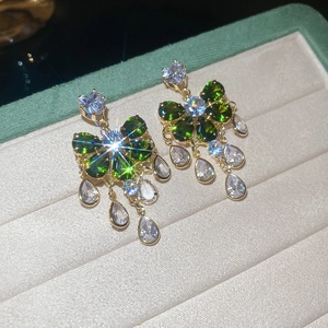 Macro view of green bow earrings with sparkling pear-cut white stones in a jewelry box