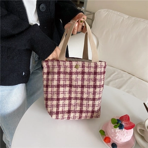 Detail of red and white checkered wool bento bag with bronze snap button and beige handles