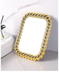 Macro detail of golden rectangular vanity mirror with vintage twisted rope metal frame