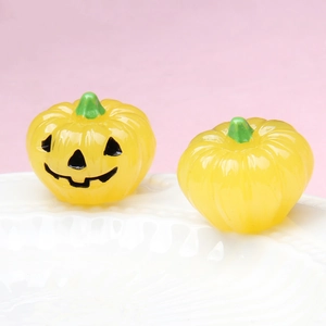 Detailed view of luminous Halloween pumpkin charms with Jack-O-Lantern faces on ceramic tray