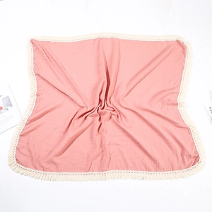 Dettaglio di una fascia per neonati in mussola di cotone rosa con frange e trama stropicciata